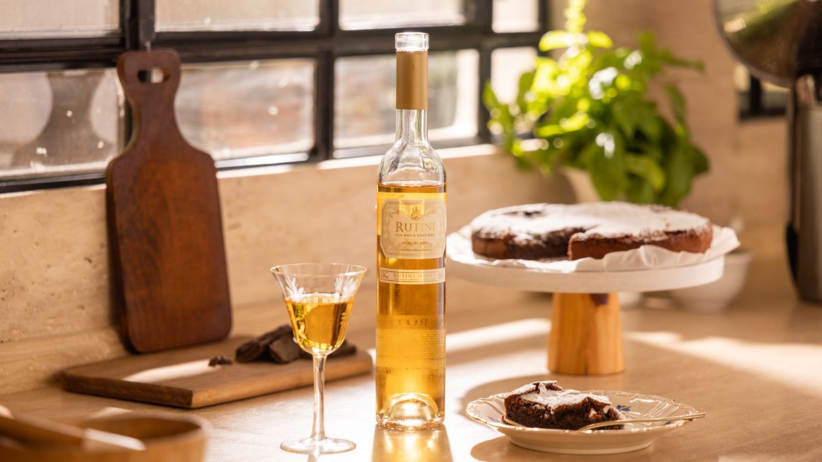 Botella de Rutini Vin Doux Naturel junto a una copa y una torta de chocolate sin harina