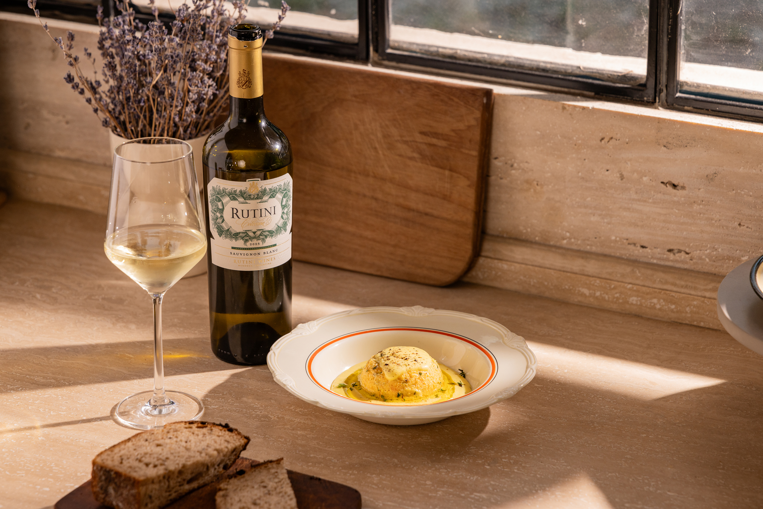 Taça de Rutini Colección Sauvignon Blanc ao lado de um flan de abóbora com fonduta de parmesão e tomilho fresco
